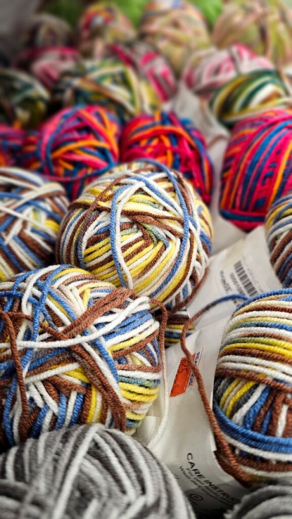 Vibrant yarn balls in various hues arranged in a craft store setting, perfect for knitting projects.
